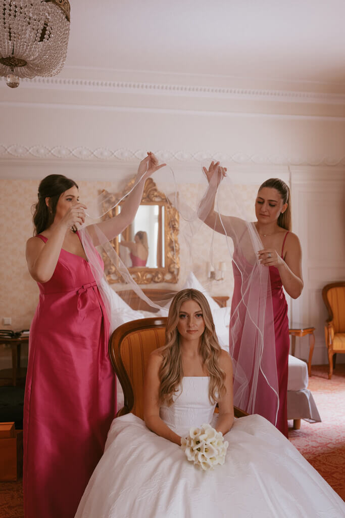 bride with her brides maids, putting the veil on